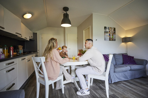 Familie sitzt an einem Esstisch in einer modernen Lodge mit Küche im Leistert Lodge, Niederlande.