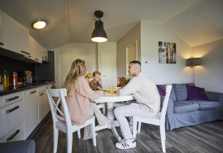 Familie sitzt an einem Esstisch in einer modernen Lodge mit Küche im Leistert Lodge, Niederlande.