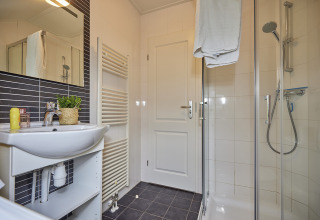 Modernes Badezimmer in der Leistert Lodge, De Leistert, Niederlande mit Dusche, Waschbecken und Handtüchern.