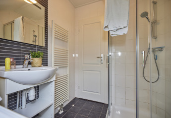 Moderne badkamer in Leistert Lodge, De Leistert, Nederland met douchecabine, lavabo en handdoeken.