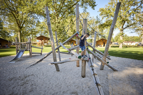 Kind spielt auf einem Kletterspielplatz bei Glamping Tent Luxe, De Leistert, Niederlande, im Grünen.