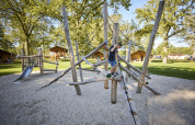 Enfant jouant sur une aire de jeux à Glamping Tent Luxe, De Leistert, Pays-Bas, entouré de nature.