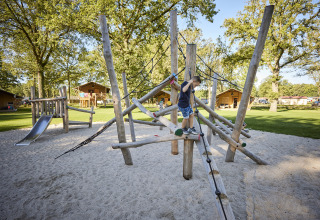 Bambino gioca su parco giochi di arrampicata al Glamping Tent Luxe, De Leistert, Olanda, nella natura.