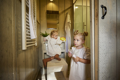 Zwei kleine Kinder putzen sich im Badezimmer eines Luxus-Glampingzeltes bei De Leistert, Niederlande, die Zähne.