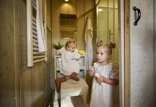 Zwei kleine Kinder putzen sich im Badezimmer eines Luxus-Glampingzeltes bei De Leistert, Niederlande, die Zähne.
