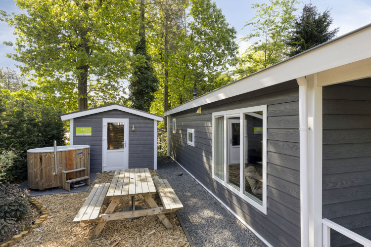 Wellness Lodge für zwei Personen bei De Thijmse Berg in den Niederlanden mit Holzbank und Whirlpool.