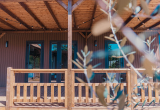 Holzveranda der Luxury Lodge im Holiday Park Sallandshoeve, Niederlande, mit Zweigen im Vordergrund.