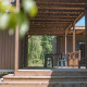 Holzterrasse mit Pergola und Sitzbereich im Luxury Lodge, umgeben von Bäumen und Natur im Sommer.