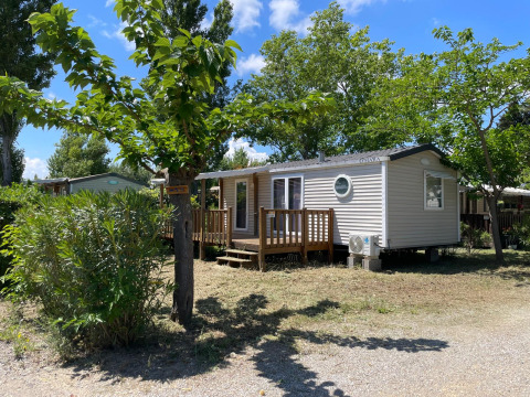 Eine Cottage-Hütte auf dem Campingplatz Seasonova Ensoya in Frankreich, umgeben von Bäumen und Natur.
