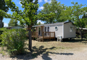 Eine Cottage-Hütte auf dem Campingplatz Seasonova Ensoya in Frankreich, umgeben von Bäumen und Natur.