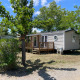 Villetta denominata Cottage al Camping Seasonova Ensoya in Francia, circondata da alberi e cielo blu.
