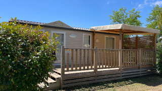 Vista exterior de una cabaña Cottage en Camping Seasonova Ensoya, Francia, con terraza de madera y sol.