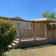 Vista esterna di una casetta Cottage al Camping Seasonova Ensoya in Francia con veranda in legno e sole.