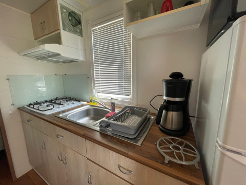 Keuken in een chalet met gasfornuis, spoelbak, koffiezet en afdruiprek op Camping Seasonova Ensoya in Frankrijk.