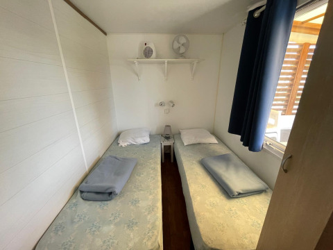 Twee eenpersoonsbedden in een lichte, gekoelde cottage bij Camping Seasonova Ensoya in Frankrijk.