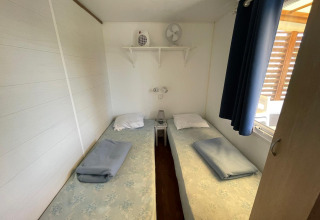 Zwei Einzelbetten in einer hellen, klimatisierten Hütte im Camping Seasonova Ensoya in Frankreich.