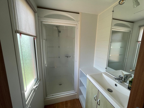 Moderne badkamer in een chalet op Camping Seasonova Ensoya in Frankrijk met douche, wasbak en raam.