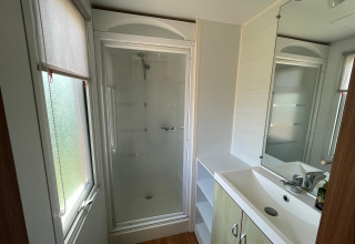 Bagno moderno in un cottage al Camping Seasonova Ensoya in Francia con doccia, lavandino e finestra.