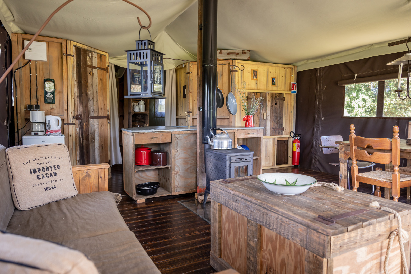 Interieur van een luxe safaritent met houten meubels en keuken bij Domaine Bonneblond in Frankrijk.
