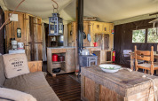 Interior of a luxury safari tent with rustic wooden furniture and kitchen at Domaine Bonneblond, France.