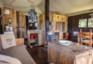 Intérieur d'une tente safari de luxe avec meubles en bois et cuisine au Domaine Bonneblond, France.