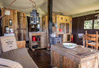 Interior de una tienda safari de lujo con muebles rústicos y cocina en Domaine Bonneblond, Francia.