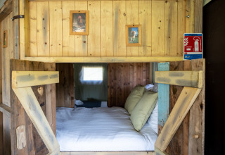 Rustiek houten nisbed met zachte kussens en dierenfoto's in Glampinglodge de luxe tent in Frankrijk.