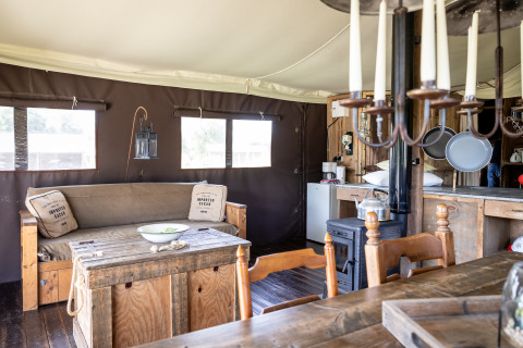 Binnenzicht van een glamping safari tent op Domaine Bonneblond in Frankrijk met houten meubels en decor.