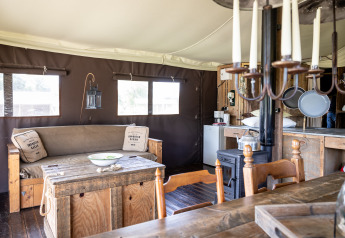 Interior de tienda glamping de lujo en Domaine Bonneblond, Francia, con muebles rústicos de madera.