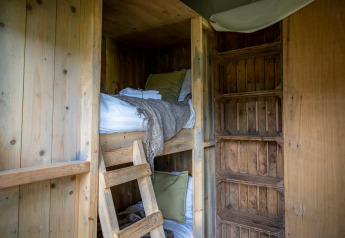 Literas de madera y ropa de cama en Glampinglodge de luxe con baño privado en Domaine Bonneblond, Francia.
