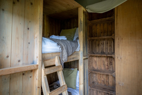 Gemütliches Holzzimmer mit Etagenbetten und Kissen im Glampinglodge de luxe bei Domaine Bonneblond, Frankreich.