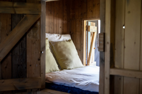 Gemütliches Bett mit großen Kissen in einem Safarizelt, Glampinglodge de luxe, Domaine Bonneblond, Frankreich.