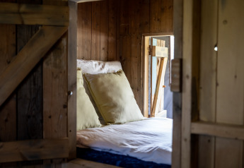 Cozy bed with large pillows inside a safari tent at Glampinglodge de luxe, Domaine Bonneblond, France.
