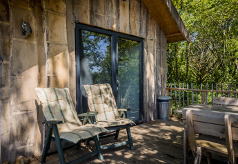 Terrasse du Boomhuis à Domaine Bonneblond en France, avec chaises longues et vue sur la forêt.