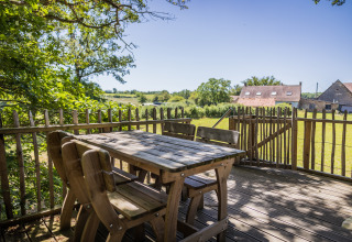 Holzterrasse des Baumhauses Boomhuis im Domaine Bonneblond, Frankreich, mit ländlicher Aussicht.
