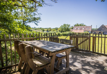 Wooden deck at the Boomhuis tree house, Domaine Bonneblond, France, with scenic countryside views.