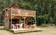 Safari tent Papillon at Domaine Bonneblond in France, featuring a wooden deck and surrounded by forest.
