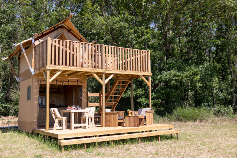 Safari tent Papillon at Domaine Bonneblond in France, featuring a wooden deck and surrounded by forest.