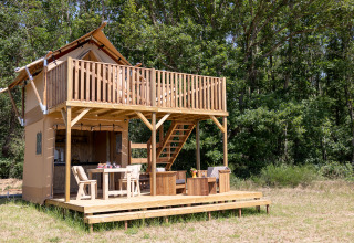 Safari tent Papillon at Domaine Bonneblond in France, featuring a wooden deck and surrounded by forest.