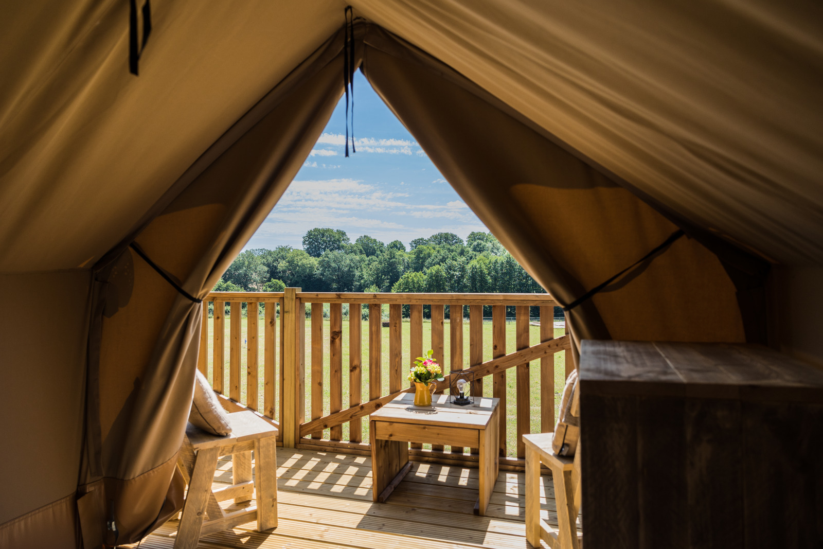 Uitzicht vanuit safaritent Papillon bij Domaine Bonneblond in Frankrijk met houten terras en groene velden.