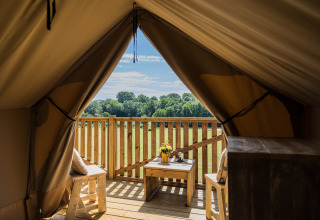 Vista desde la tienda safari Papillon en Domaine Bonneblond, Francia, con terraza de madera y campo verde.