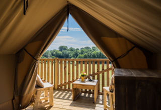 View from the Papillon safari tent at Domaine Bonneblond, France, featuring a wooden deck and scenic fields.