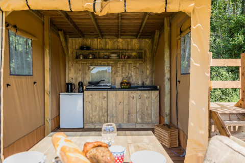 Kitchen area of the Papillon safari tent at Domaine Bonneblond in France, with wooden furniture and appliances.