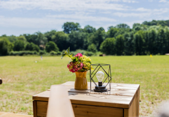 Vista desde la tienda safari Papillon en Domaine Bonneblond, Francia, con flores y lámpara sobre la mesa.
