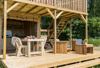 Træterrasse med spiseplads og lounge ved safaritelten Papillon på Domaine Bonneblond i Frankrig.