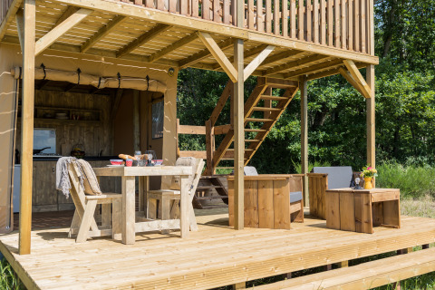 Wooden terrace with dining and lounge area at safari tent Papillon at Domaine Bonneblond in France.