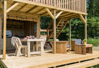 Terraza de madera con comedor y salón en la tienda safari Papillon de Domaine Bonneblond en Francia.