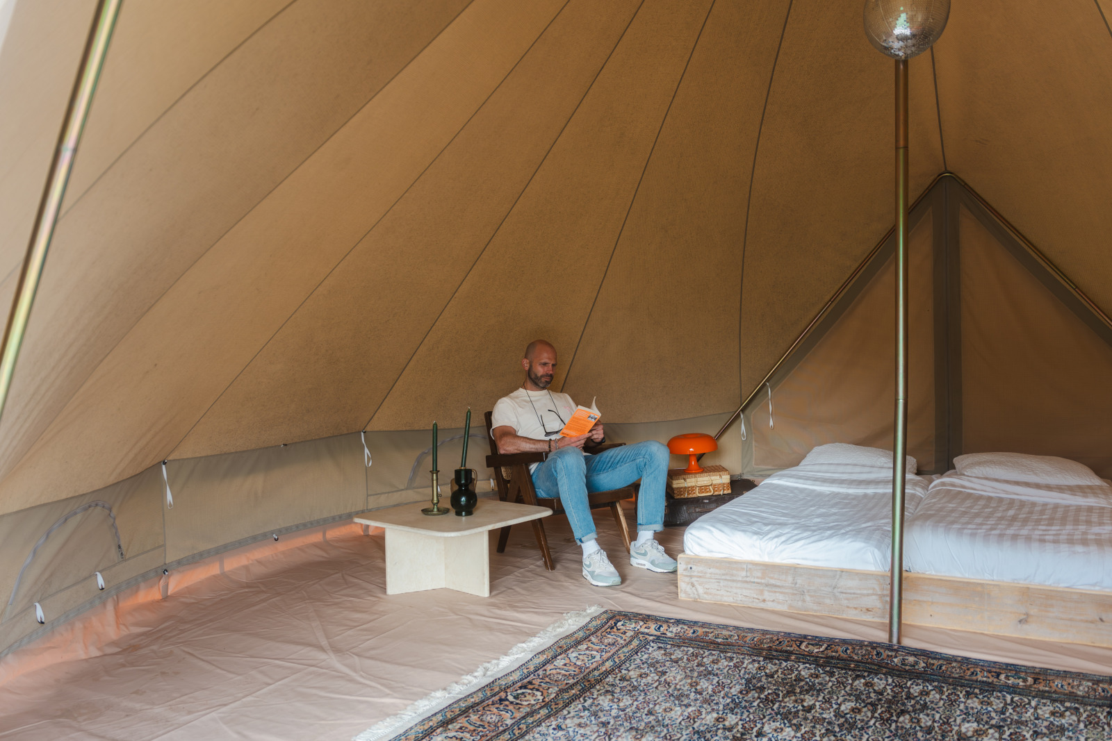 Binnen in een Bell tent bij Domaine Bonneblond in Frankrijk zit een man een boek te lezen naast het bed.