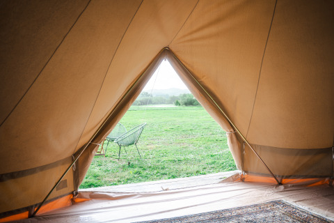 Blick aus einem Zelt auf eine grüne Wiese bei den Bell Tents im Domaine Bonneblond, Frankreich.