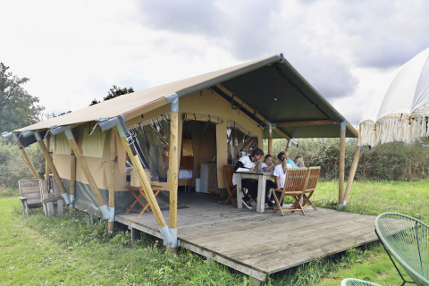 Famiglia si gode la veranda di una tenda safari con servizi privati al Domaine Bonneblond, Francia, nella natura.